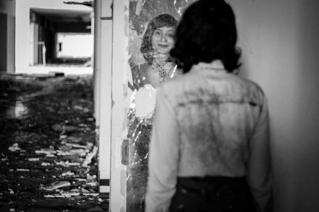Fragmented reflection of a figure in a broken mirror