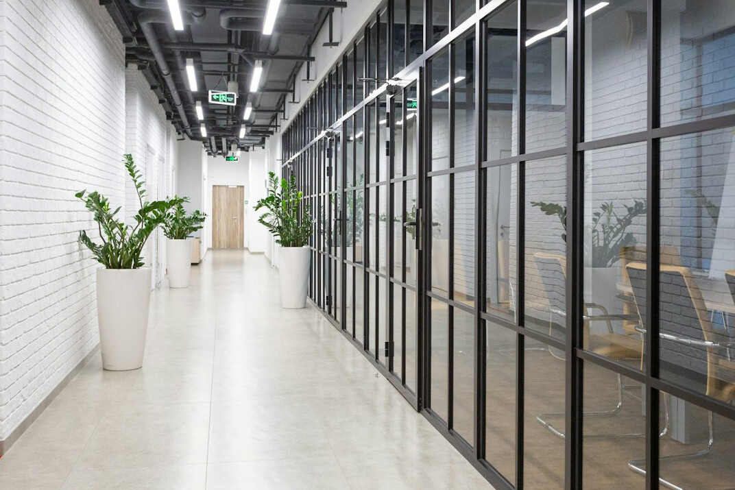 Quiet editorial office corridor with glass doors and soft light